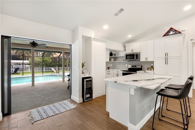 kitchen featuring white cabinetry, ceiling fan, wine cooler, lofted ceiling, and appliances with stainless steel finishes