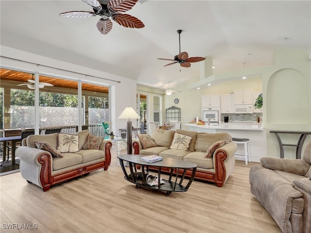 living room with french doors, light wood-type flooring, lofted ceiling, and sink