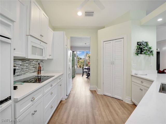 kitchen featuring decorative backsplash, white cabinetry, black electric cooktop, and light hardwood / wood-style floors