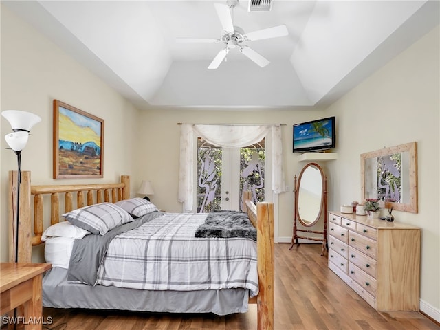 bedroom with a raised ceiling, ceiling fan, wood-type flooring, and vaulted ceiling