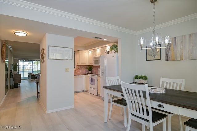 dining space with light hardwood / wood-style flooring, ornamental molding, and a notable chandelier