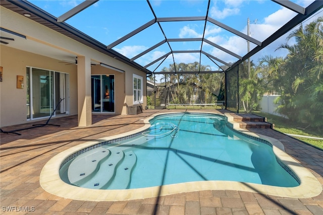 view of pool with a patio, glass enclosure, and ceiling fan