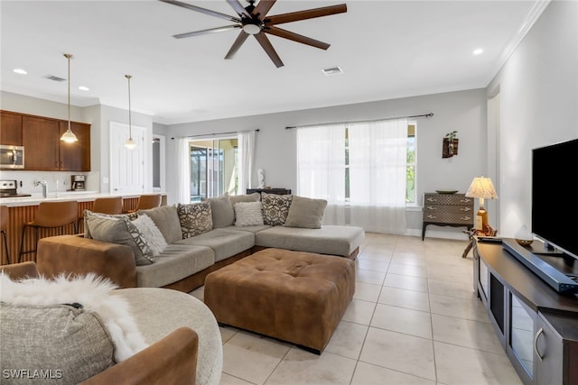 living room featuring ceiling fan, sink, light tile patterned floors, and crown molding