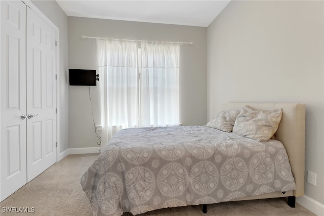 bedroom featuring light colored carpet and a closet