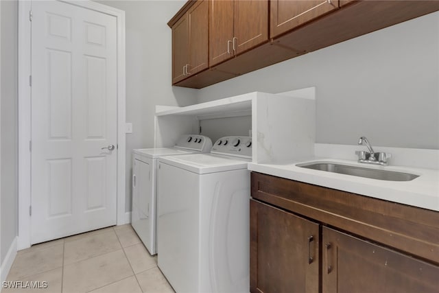 clothes washing area featuring cabinets, washing machine and dryer, light tile patterned floors, and sink