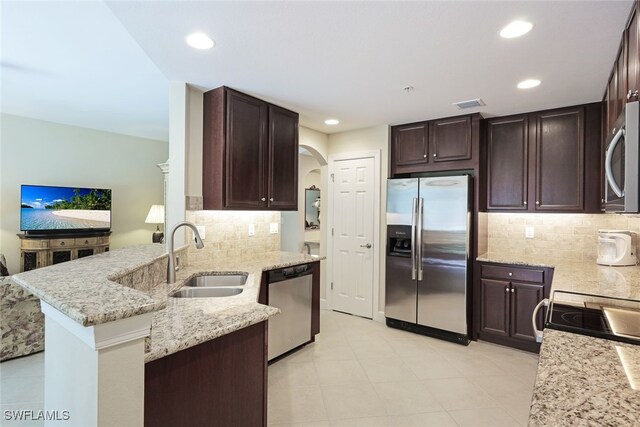 kitchen with backsplash, sink, appliances with stainless steel finishes, light stone counters, and kitchen peninsula