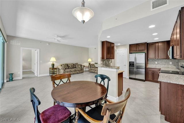 tiled dining space with ceiling fan and sink