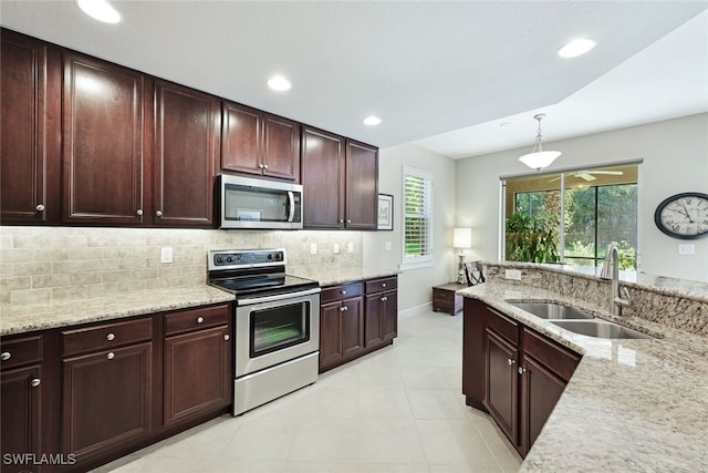 kitchen featuring sink, stainless steel appliances, tasteful backsplash, light stone counters, and pendant lighting