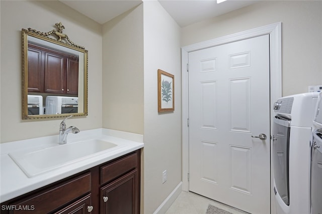 laundry area featuring washer and clothes dryer, light tile patterned flooring, cabinets, and sink