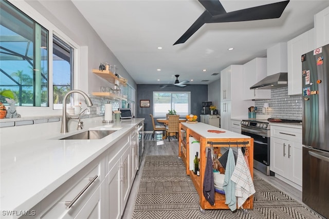 kitchen featuring white cabinetry, dark wood-type flooring, wall chimney range hood, and appliances with stainless steel finishes