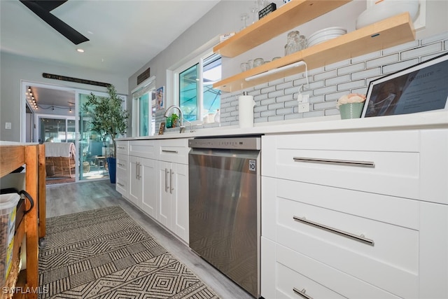 kitchen with sink, stainless steel dishwasher, decorative backsplash, white cabinets, and light wood-type flooring