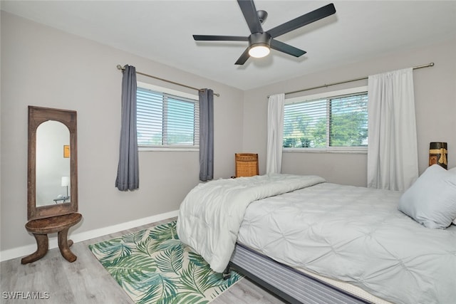 bedroom with multiple windows, ceiling fan, and hardwood / wood-style floors