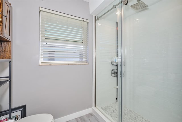 bathroom featuring wood-type flooring, toilet, and a shower with shower door