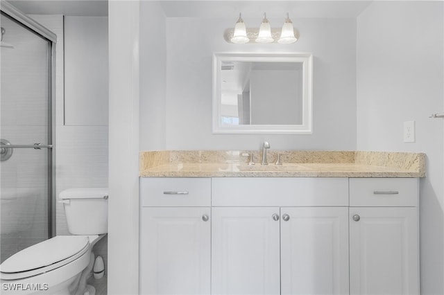 bathroom featuring vanity, a shower with shower door, and toilet