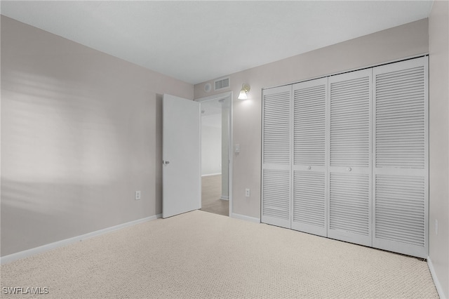 unfurnished bedroom featuring light colored carpet and a closet