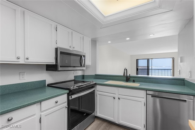 kitchen featuring hardwood / wood-style flooring, sink, white cabinets, and appliances with stainless steel finishes