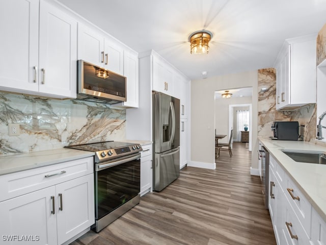 kitchen with appliances with stainless steel finishes, tasteful backsplash, light stone counters, dark hardwood / wood-style floors, and white cabinetry