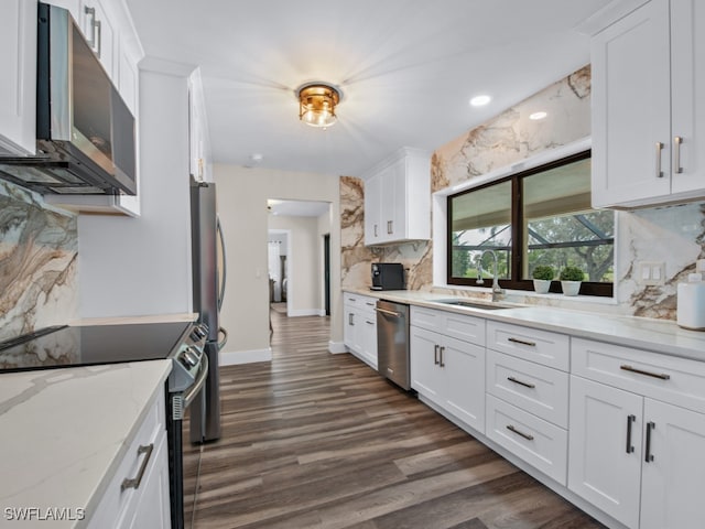 kitchen with tasteful backsplash, white cabinetry, light stone counters, and appliances with stainless steel finishes