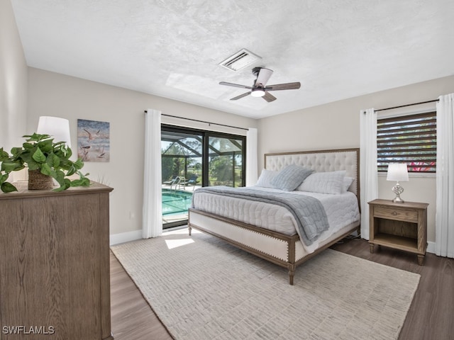 bedroom with access to exterior, ceiling fan, dark wood-type flooring, and a textured ceiling