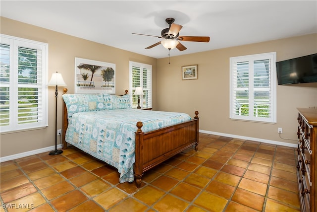 tiled bedroom with ceiling fan and multiple windows