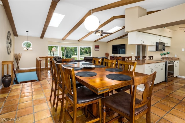 dining area with ceiling fan, vaulted ceiling with skylight, and light tile patterned flooring