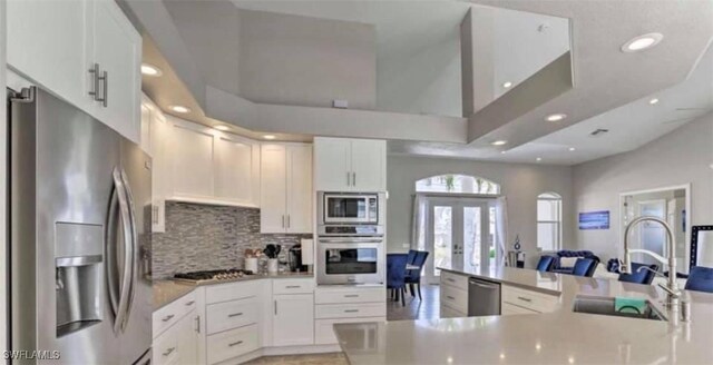 kitchen featuring decorative backsplash, french doors, white cabinets, and stainless steel appliances