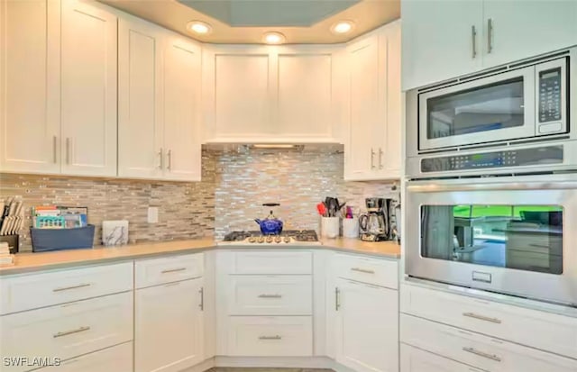 kitchen featuring backsplash, white cabinetry, and stainless steel appliances