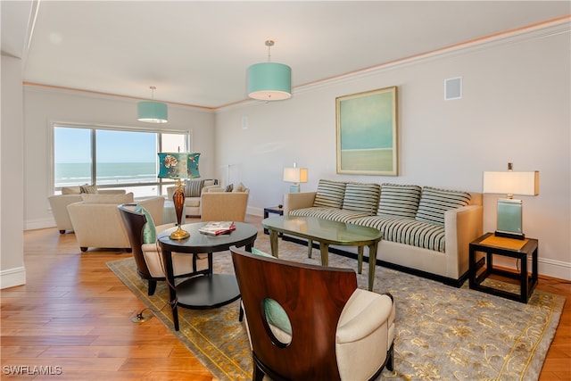 living room featuring light wood-type flooring, crown molding, and a water view