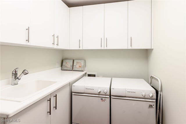 clothes washing area featuring sink, separate washer and dryer, and cabinets