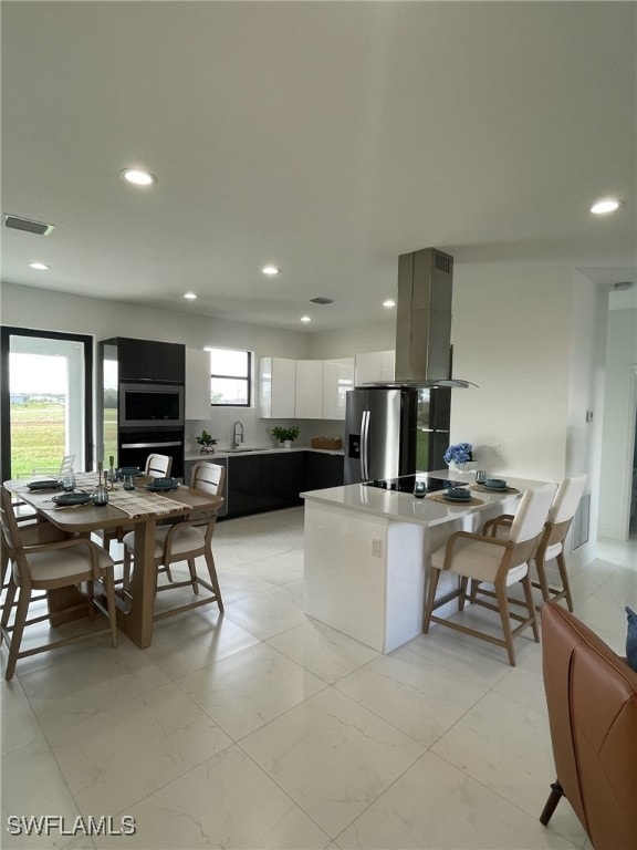 kitchen featuring white cabinetry, sink, stainless steel appliances, kitchen peninsula, and island range hood