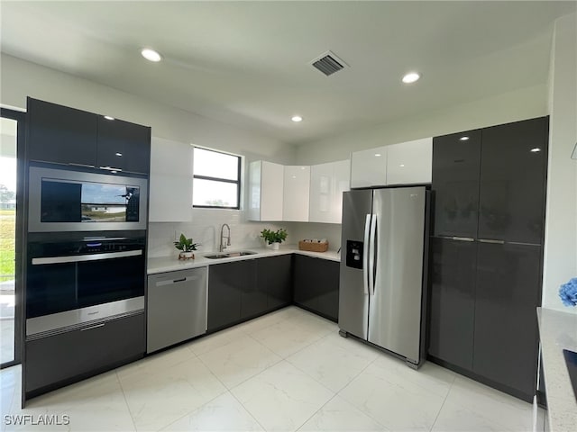 kitchen with white cabinets, stainless steel appliances, tasteful backsplash, and sink