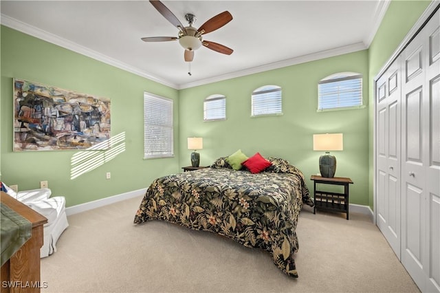 carpeted bedroom with ceiling fan, ornamental molding, and a closet