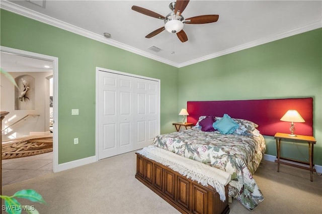 carpeted bedroom with a closet, ceiling fan, and crown molding