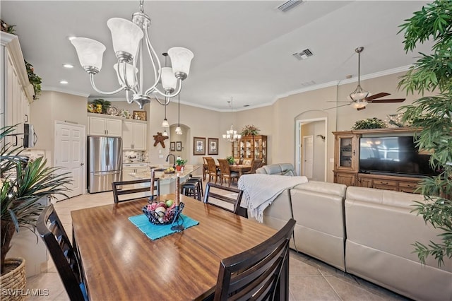 tiled dining room with ornamental molding, sink, and ceiling fan with notable chandelier