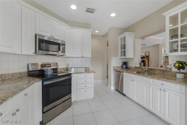 kitchen with decorative backsplash, appliances with stainless steel finishes, light stone countertops, sink, and white cabinets