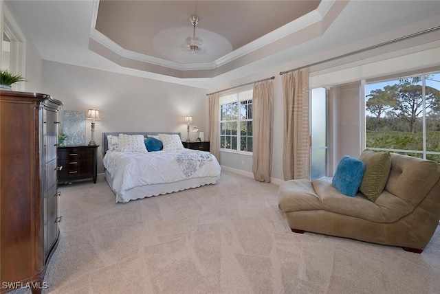 carpeted bedroom with ceiling fan, a raised ceiling, and crown molding