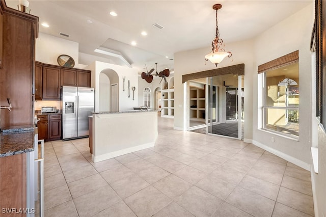 kitchen featuring pendant lighting, dark stone countertops, stainless steel fridge with ice dispenser, and light tile patterned floors