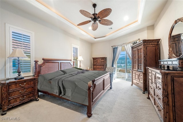 carpeted bedroom with access to exterior, a tray ceiling, and ceiling fan