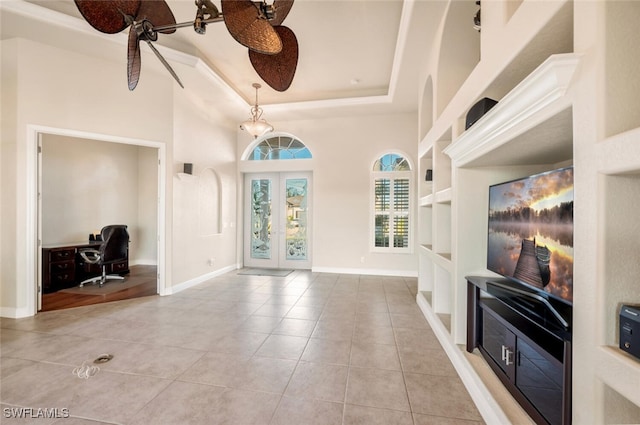 living room with french doors, a tray ceiling, built in features, and light tile patterned floors