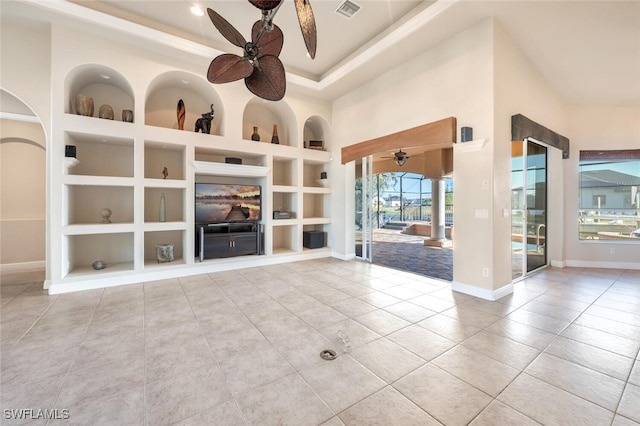 unfurnished living room with a tray ceiling, built in features, ceiling fan, and light tile patterned flooring