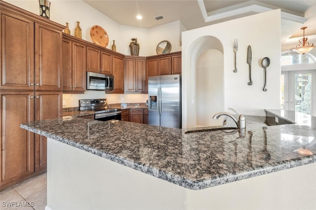 kitchen featuring french doors, appliances with stainless steel finishes, light tile patterned floors, and dark stone counters