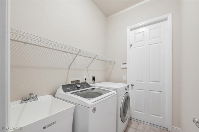 laundry room with washing machine and clothes dryer, sink, and light tile patterned floors