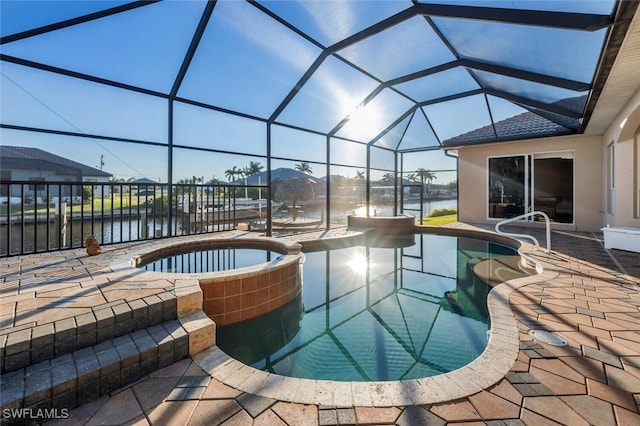 view of pool featuring an in ground hot tub, a water view, glass enclosure, and a patio area