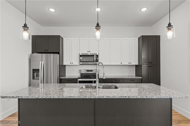 kitchen with appliances with stainless steel finishes, white cabinetry, and pendant lighting