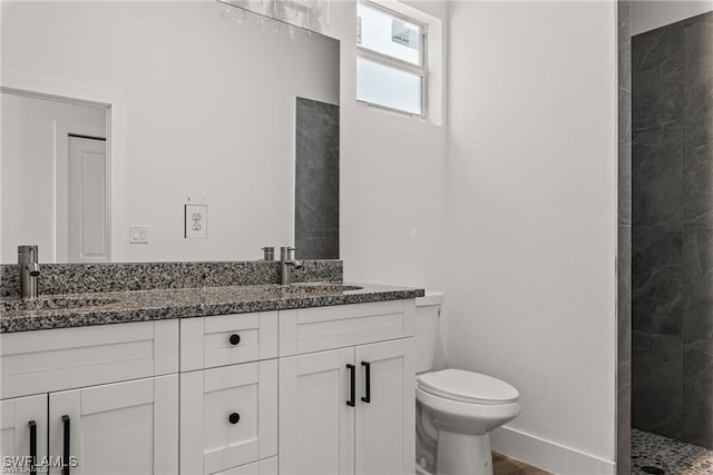 bathroom with vanity, toilet, and a tile shower