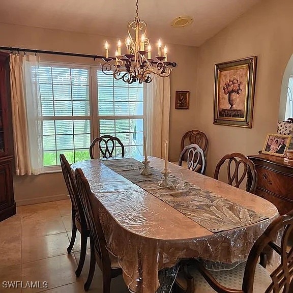 dining space featuring vaulted ceiling, a notable chandelier, and light tile patterned flooring