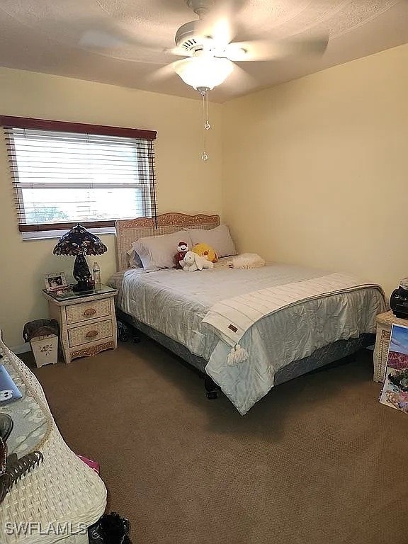 bedroom with dark colored carpet and ceiling fan