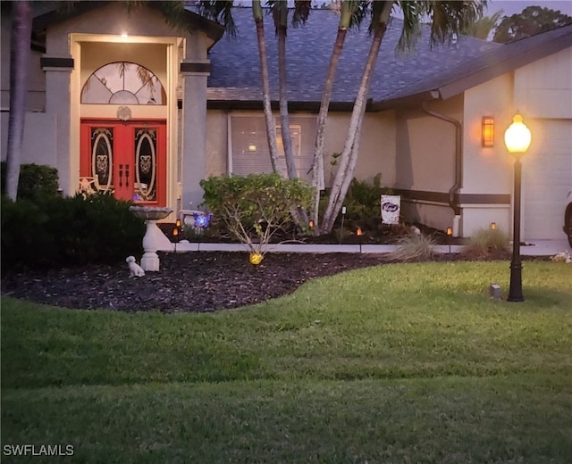 view of exterior entry with stucco siding and a yard