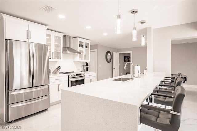 kitchen featuring sink, stainless steel appliances, wall chimney range hood, decorative light fixtures, and white cabinets