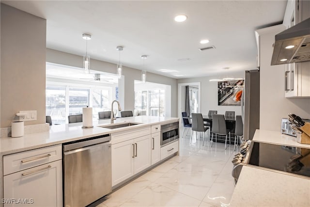 kitchen with white cabinetry, sink, hanging light fixtures, ventilation hood, and appliances with stainless steel finishes